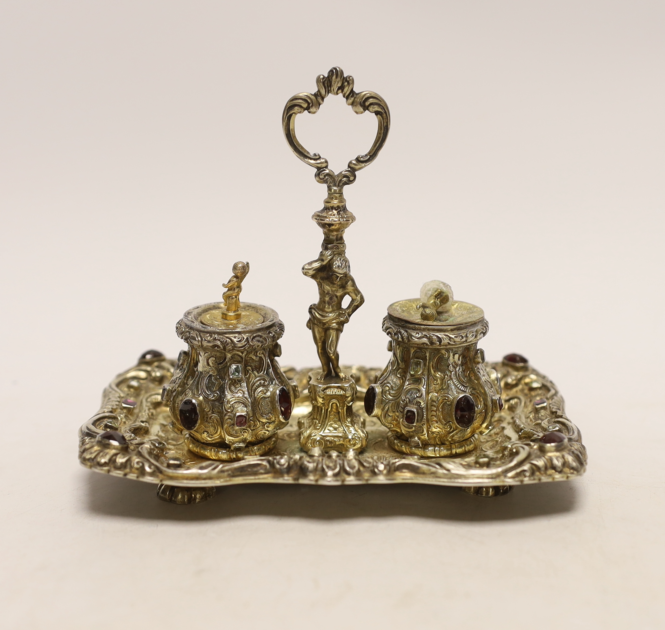 A 19th century Austrian embossed gilt white metal and multi gem set rectangular inkstand, with ring handle and two wells, 14.2cm, gross weight 6.3oz (a.f.).